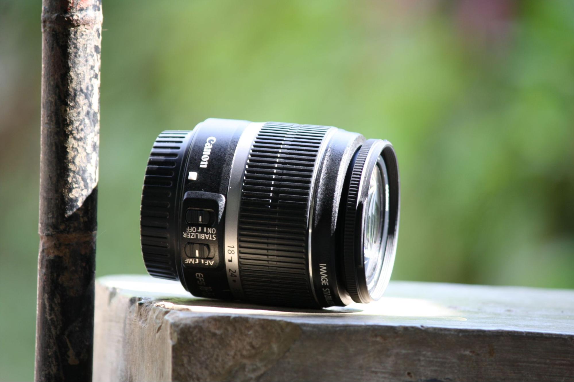 Canon lens on a concrete ledge with a blurred green background