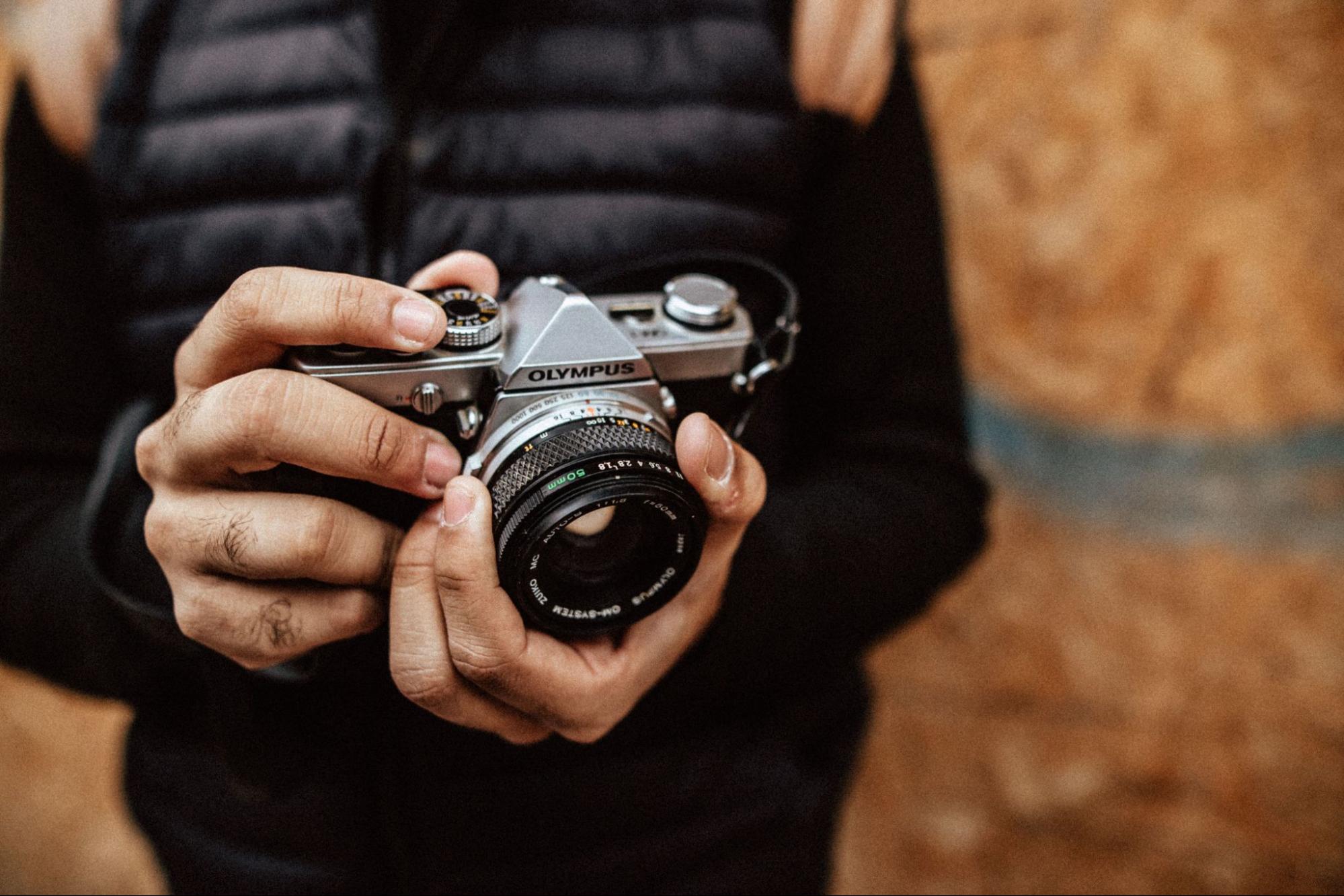 Hands holding an Olympus film camera set to manual exposure