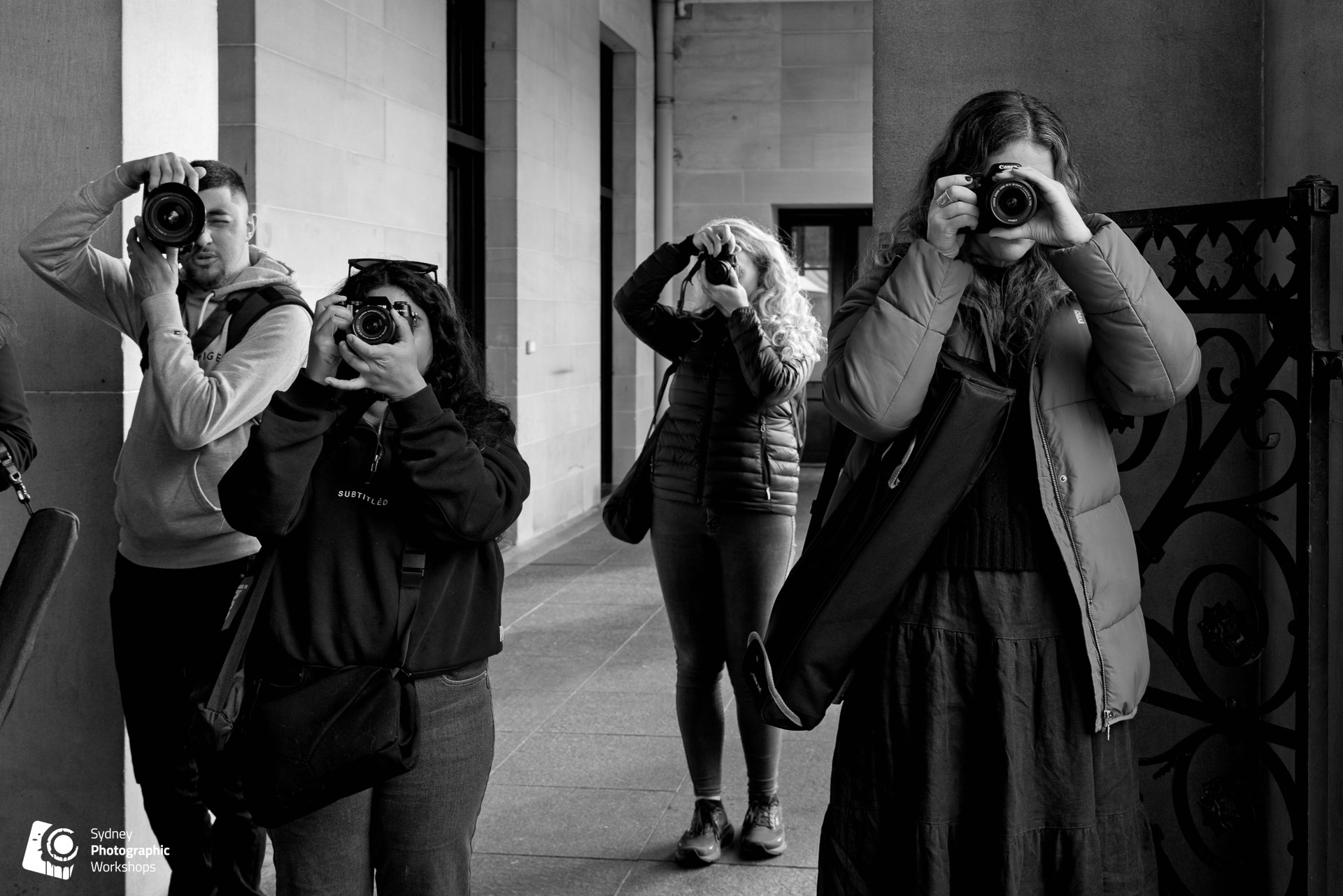 A group of beginner photographers shooting together in a Sydney sandstone colonnade