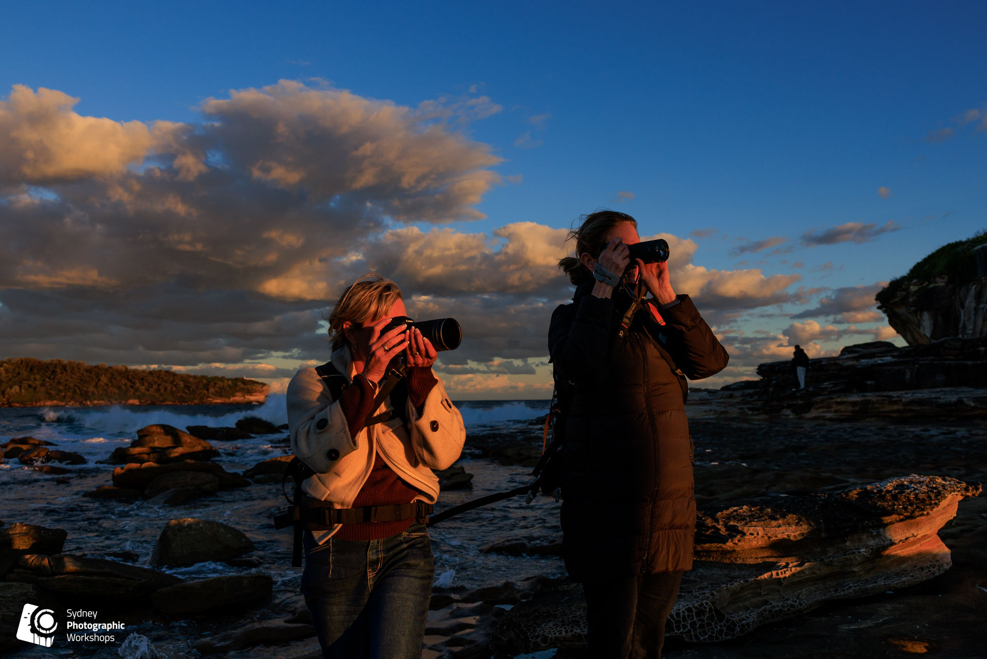 Two photographers shooting the coastline at golden hour near Sydney